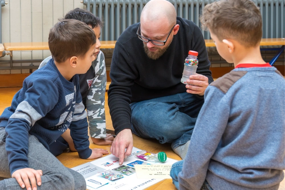 Un animateur COSEDEC présente le cycle du recyclage à des enfants dans le cadre de l’animation scolaire De l’or dans nos poubelles.