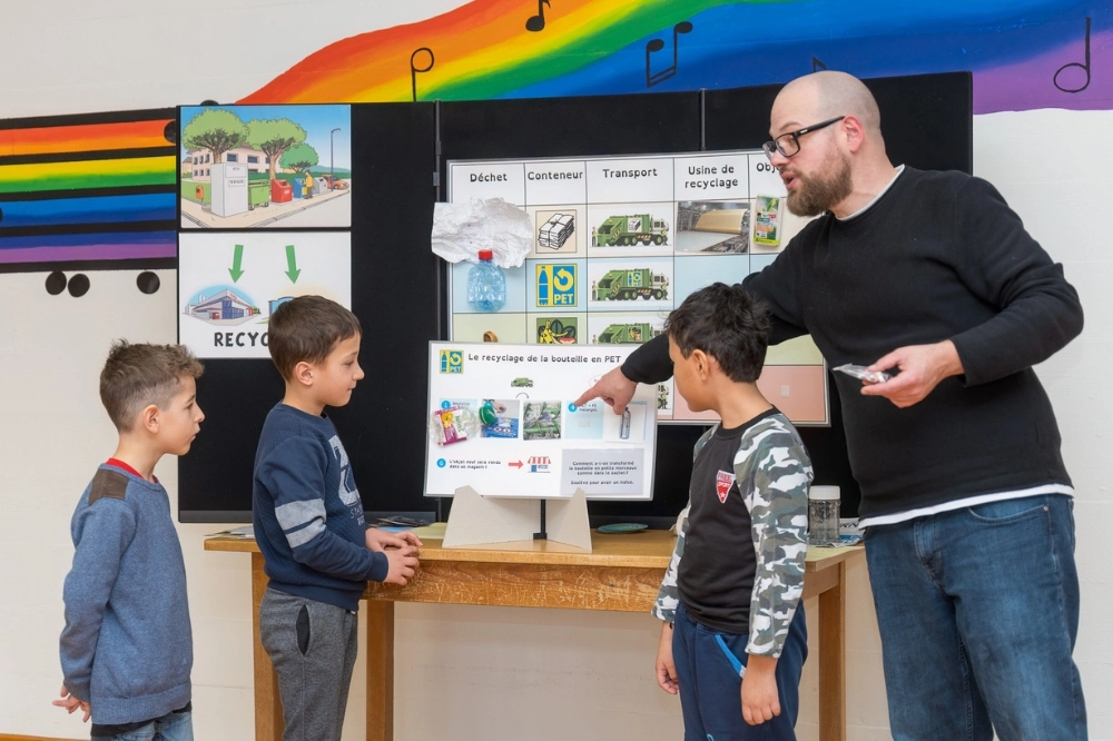 Un animateur COSEDEC présente le cycle du recyclage à des enfants dans le cadre de l’animation scolaire De l’or dans nos poubelles.