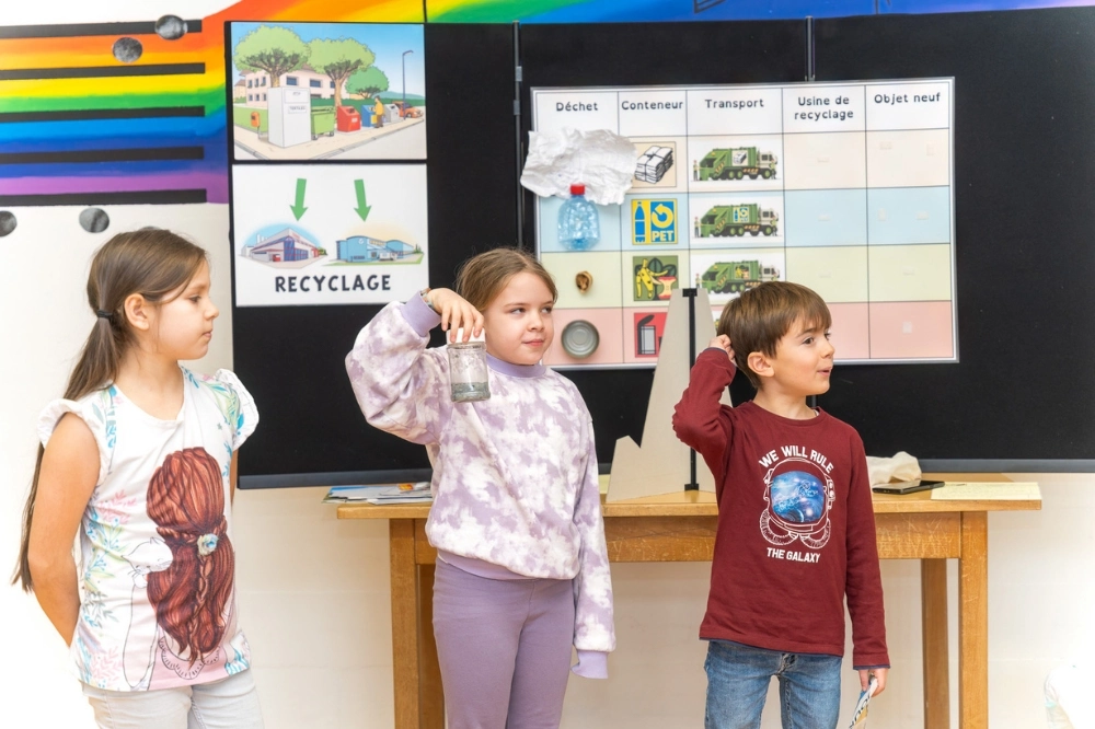 Un animateur COSEDEC présente le cycle du recyclage à des enfants dans le cadre de l’animation scolaire De l’or dans nos poubelles.