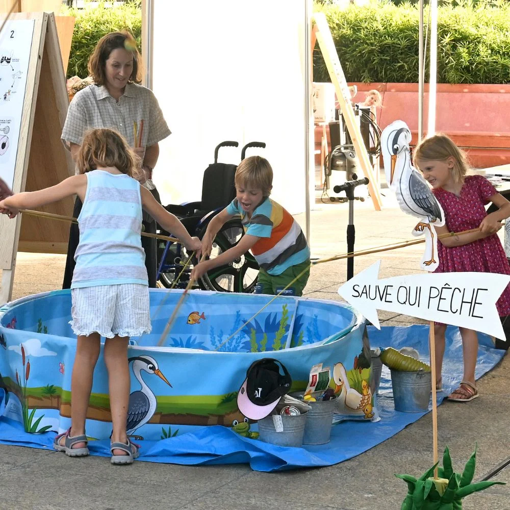 Lors d’une animation COSEDEC, des enfants pêchent des déchets dans un bassin pour comprendre les effets du littering sur un biotope.