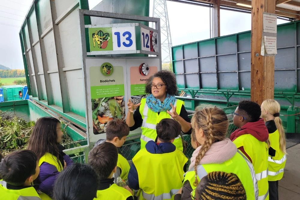 Une animatrice présente à des élèves les filières des biodéchets et de la ferraille lors d’une visite en déchèterie